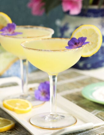 Two glasses of lemon drop martinis are placed on a white plate.
