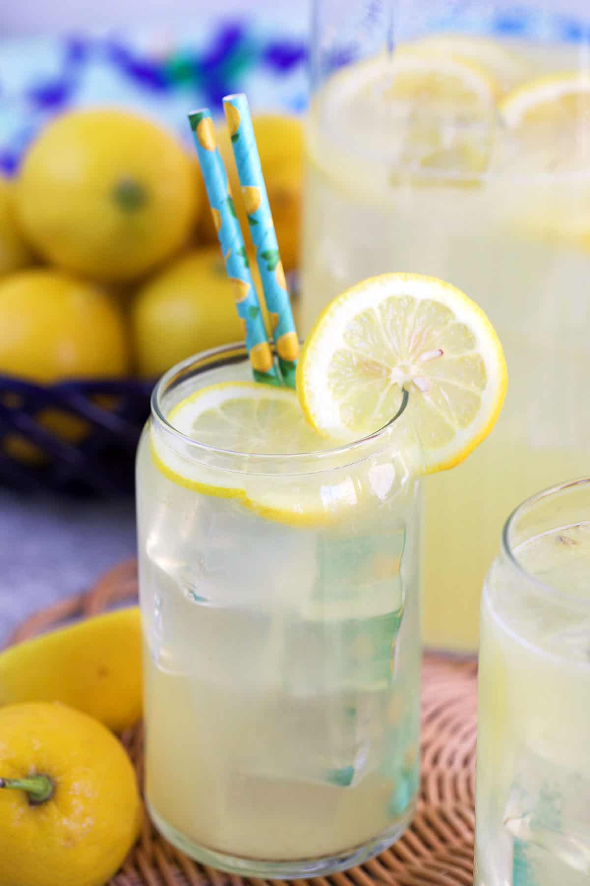 glass of lemonade with a lemon slice and blue straws.