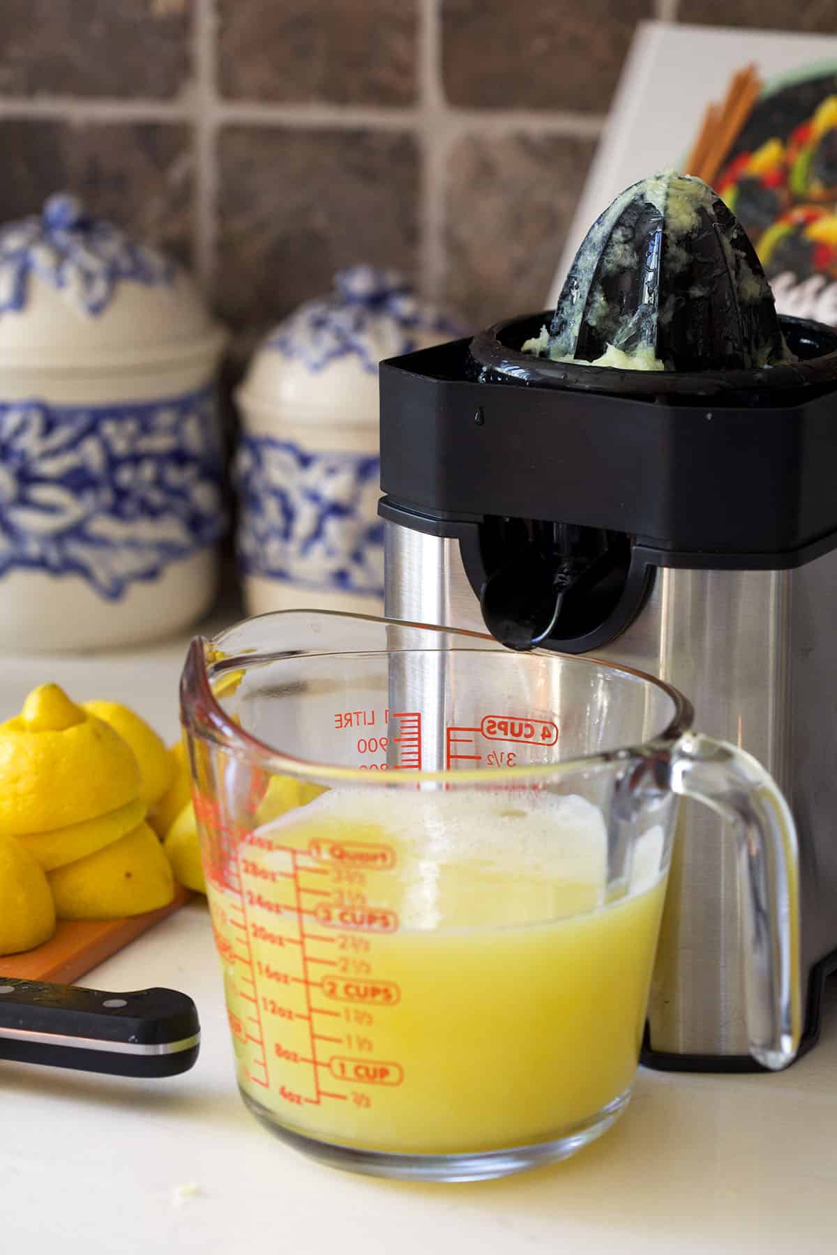 electric juicer with a pitcher of lemon juice in front of the spout