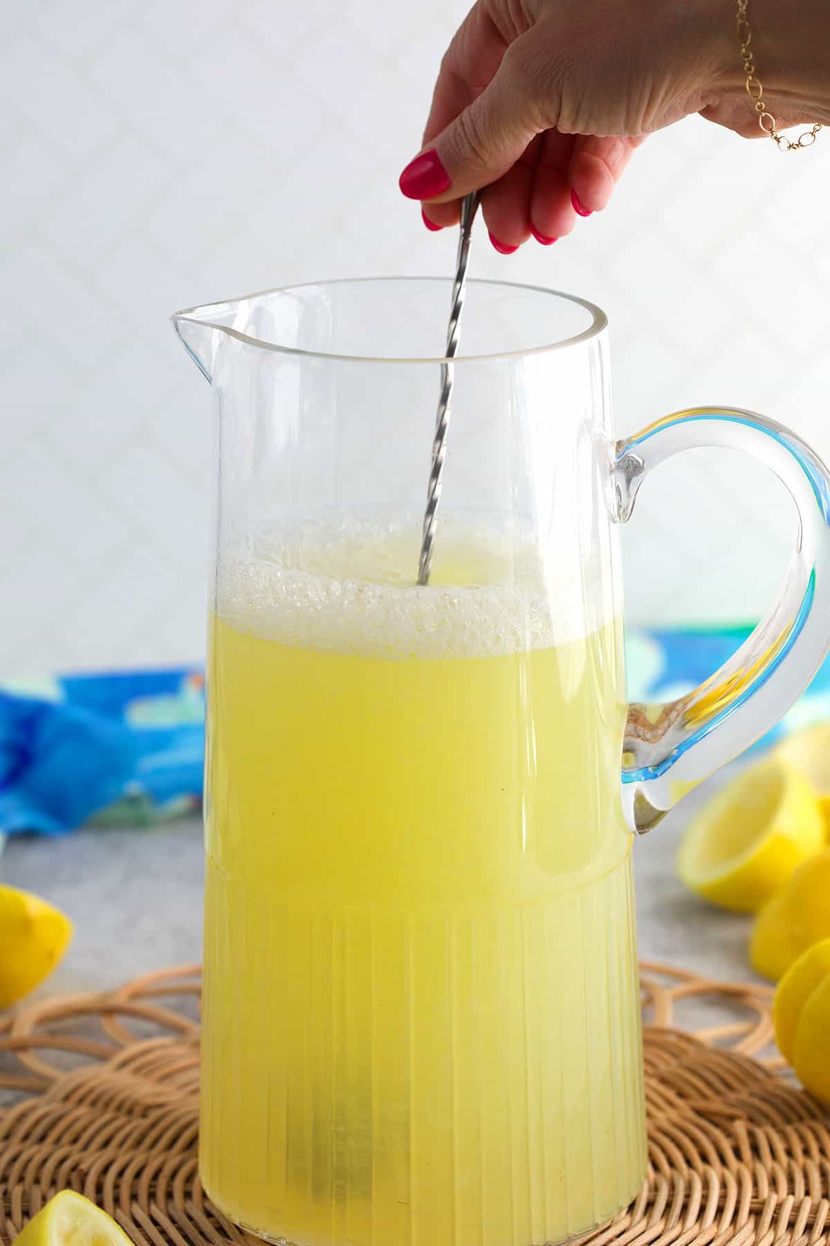 Lemonade being stirred in a glass pitcher.
