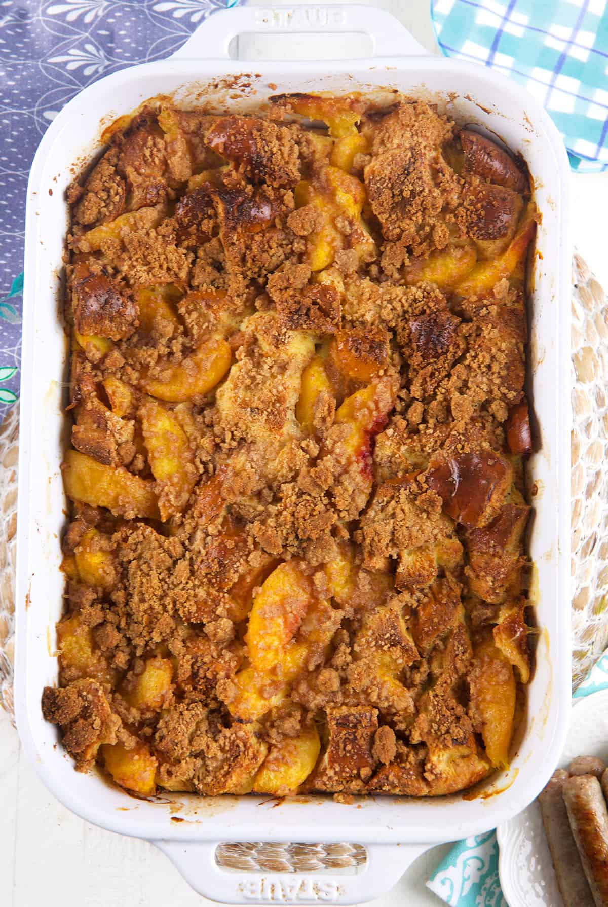 A large white baking dish is filled with peach cobbler french toast. 