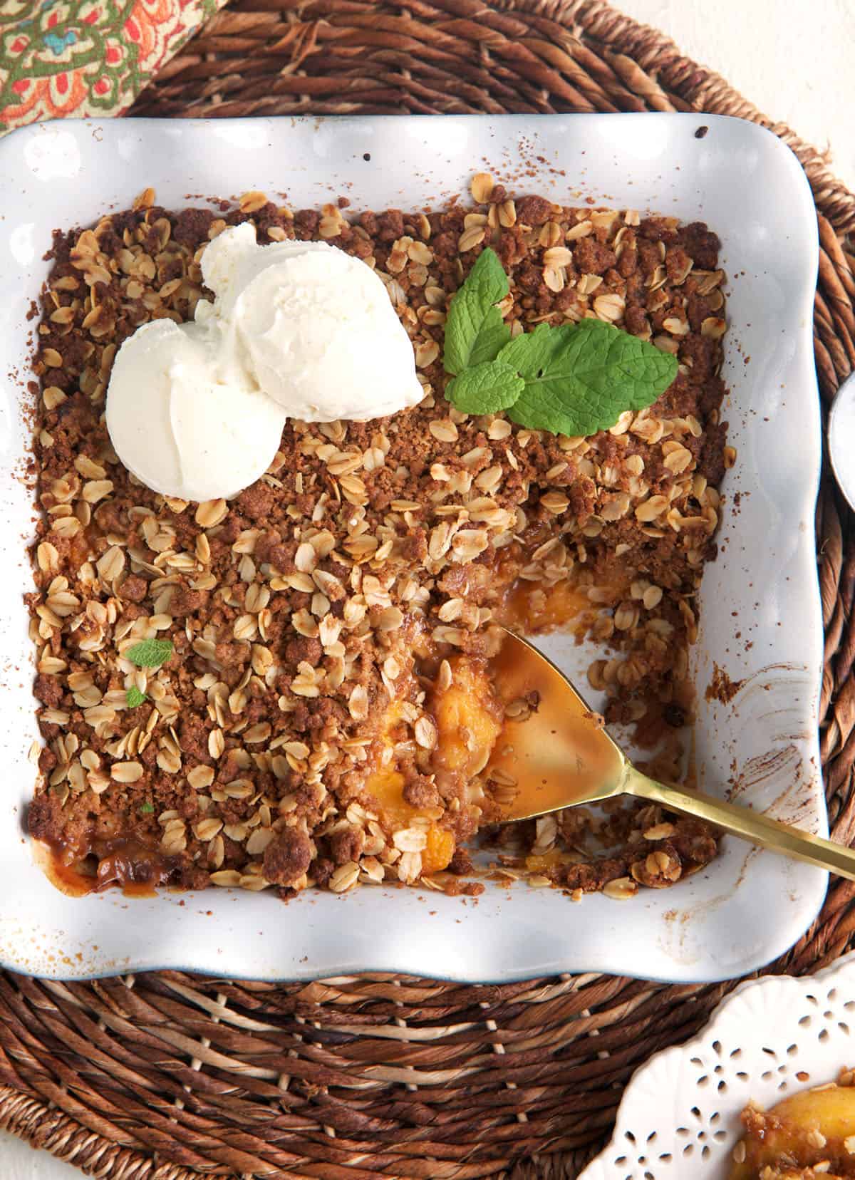 Two scoops of ice cream are placed on top of a peach crisp. 