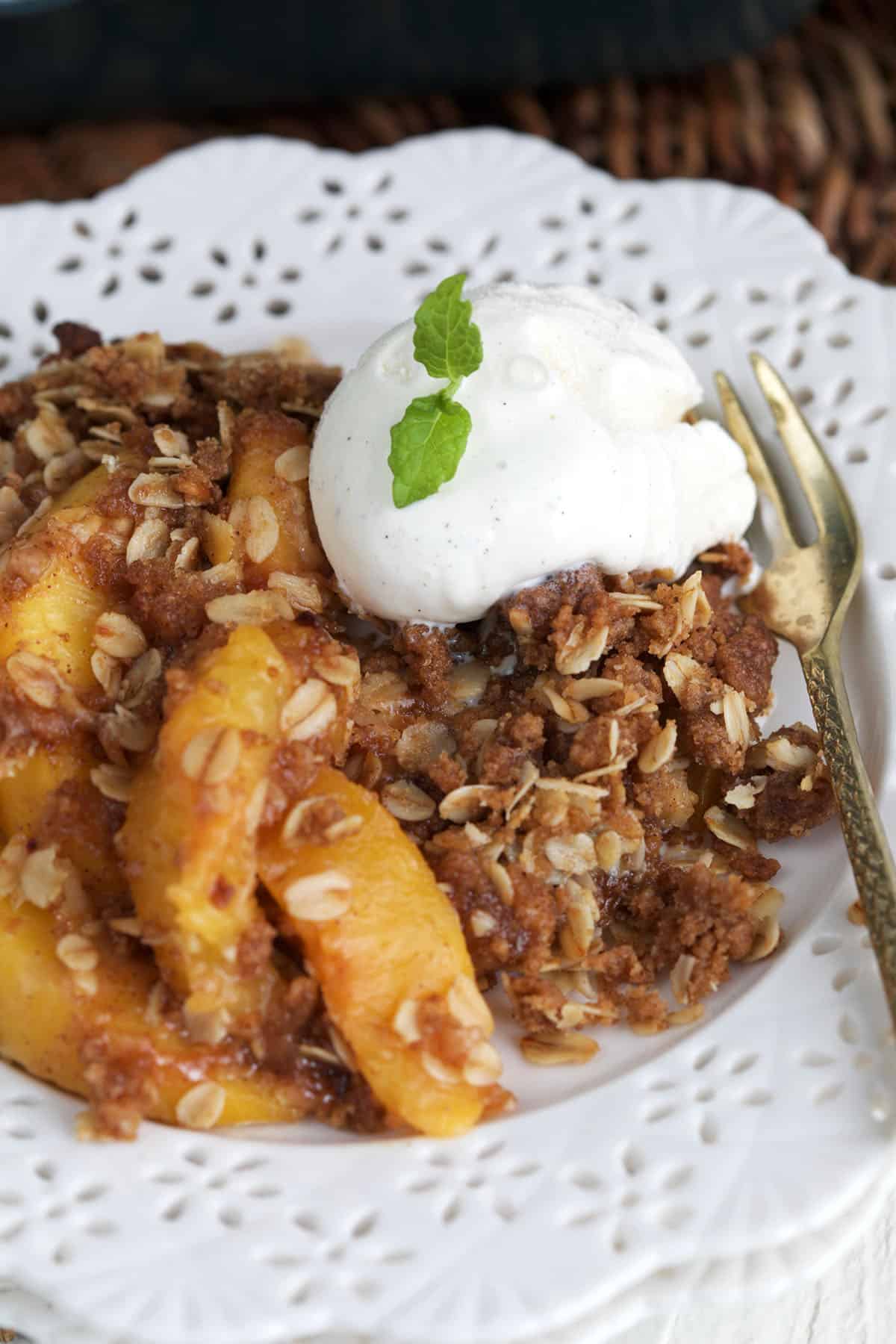 A serving of peach crisp is placed on a white plate. 