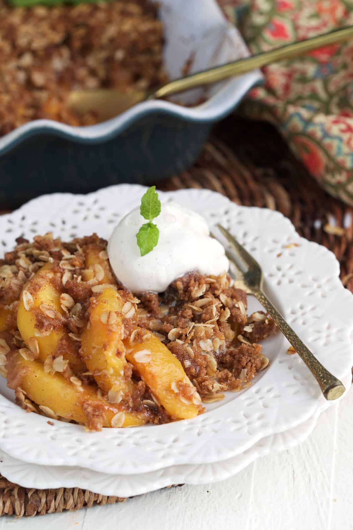 A white plate is topped with peach crisp and a fork. 