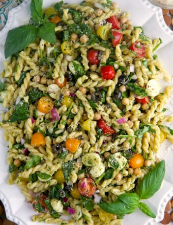 A large white platter is topped with pesto pasta salad.