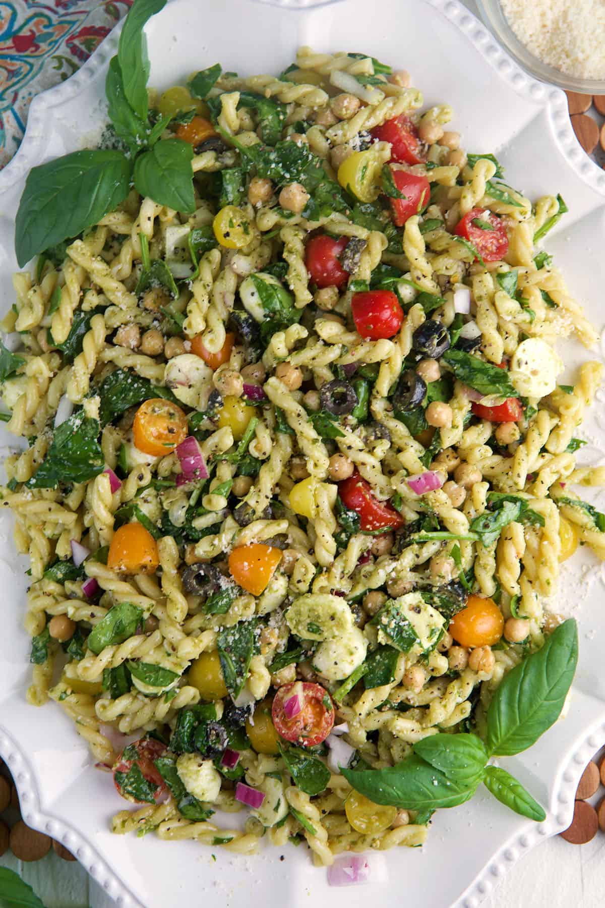 A large white platter is topped with pesto pasta salad. 