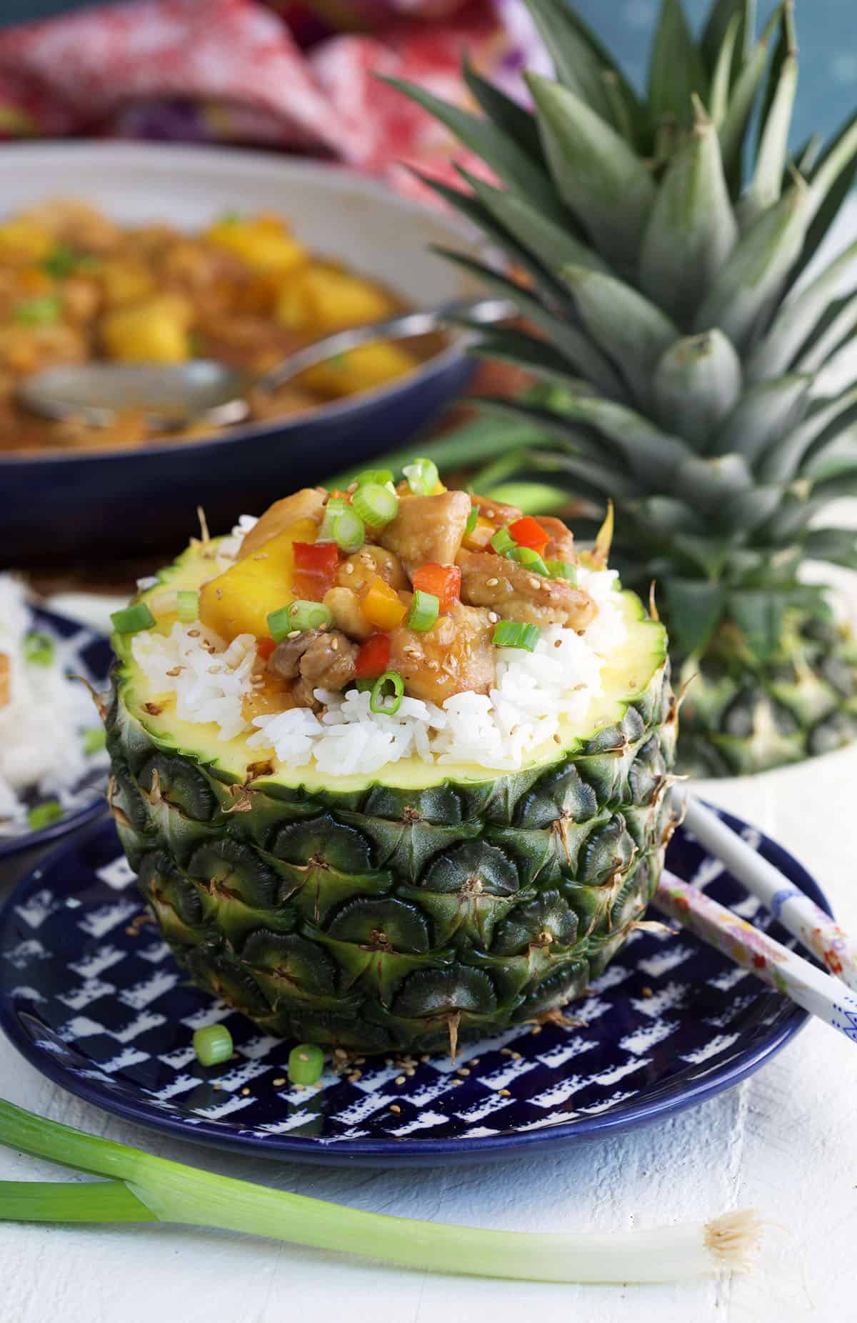 A pineapple is filled with rice and pineapple chicken. 