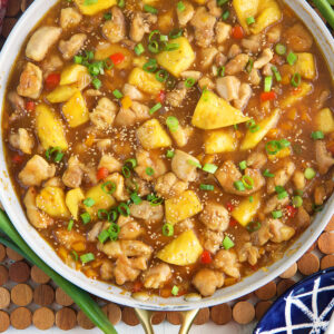 A skillet is filled with cooked pineapple chicken.