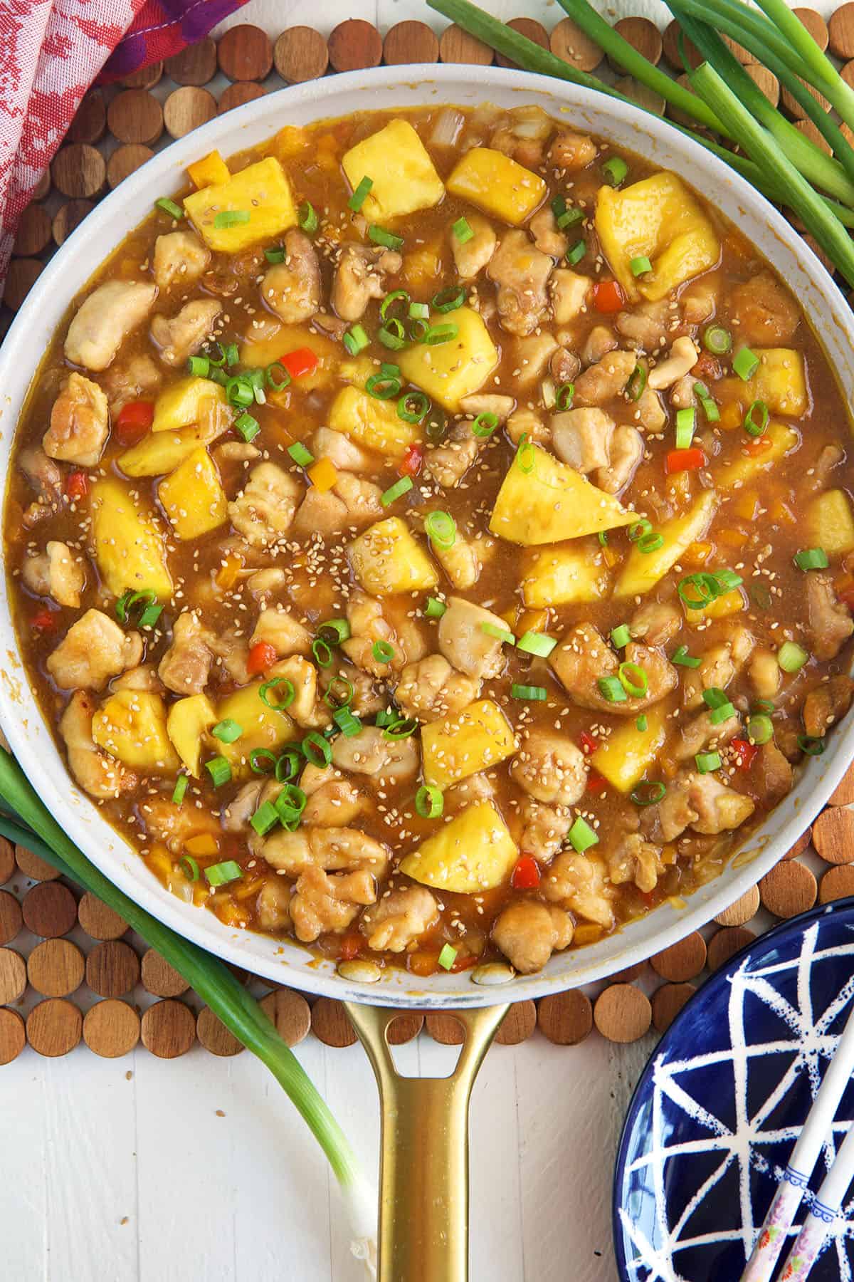A skillet is filled with cooked pineapple chicken. 
