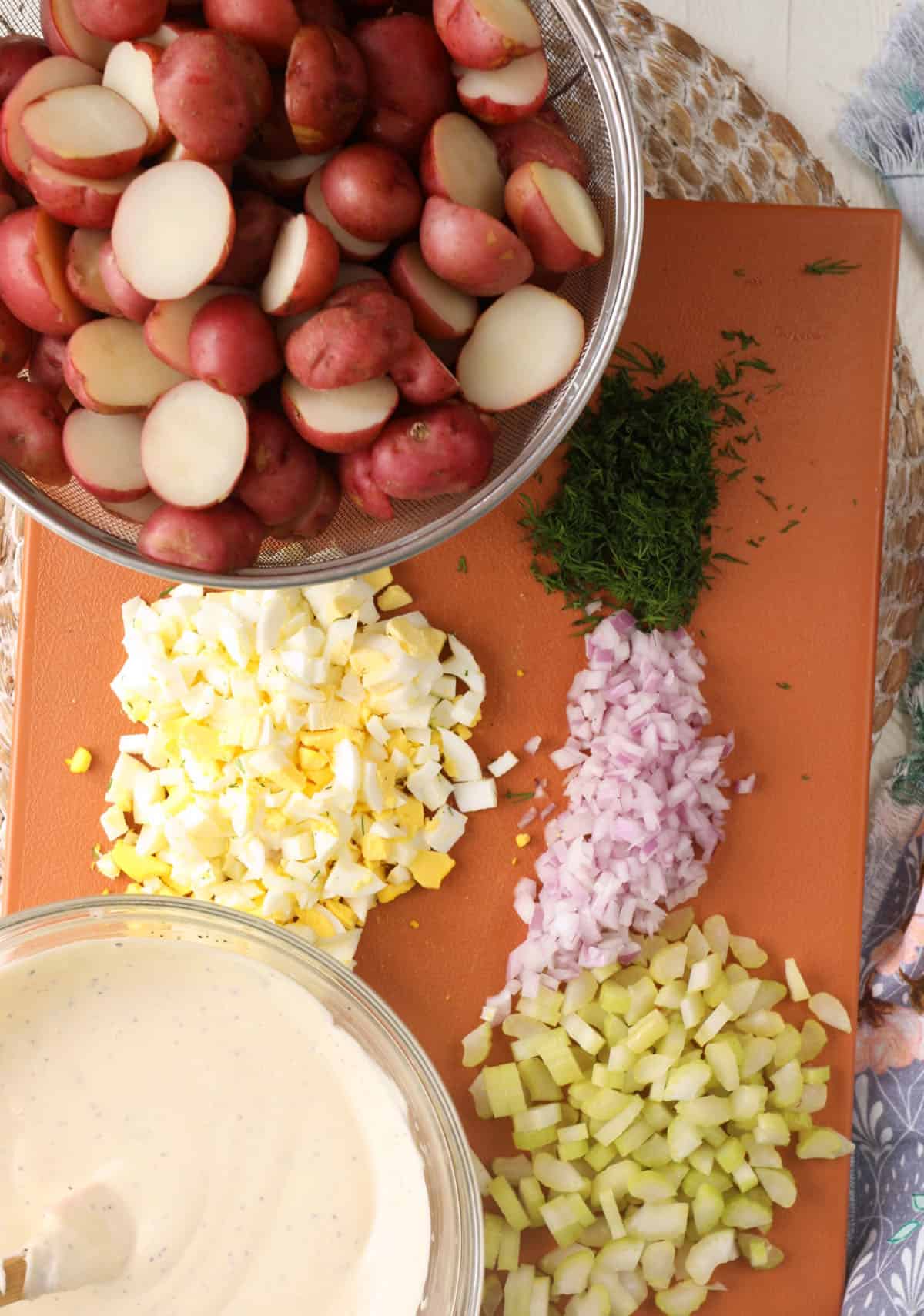 The ingredients for red potato salad are on a cutting board. 