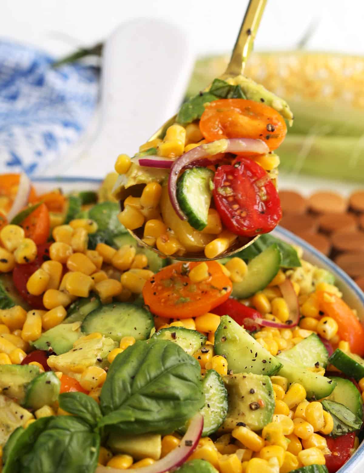 Spoonful of avocado corn salad held over bowl