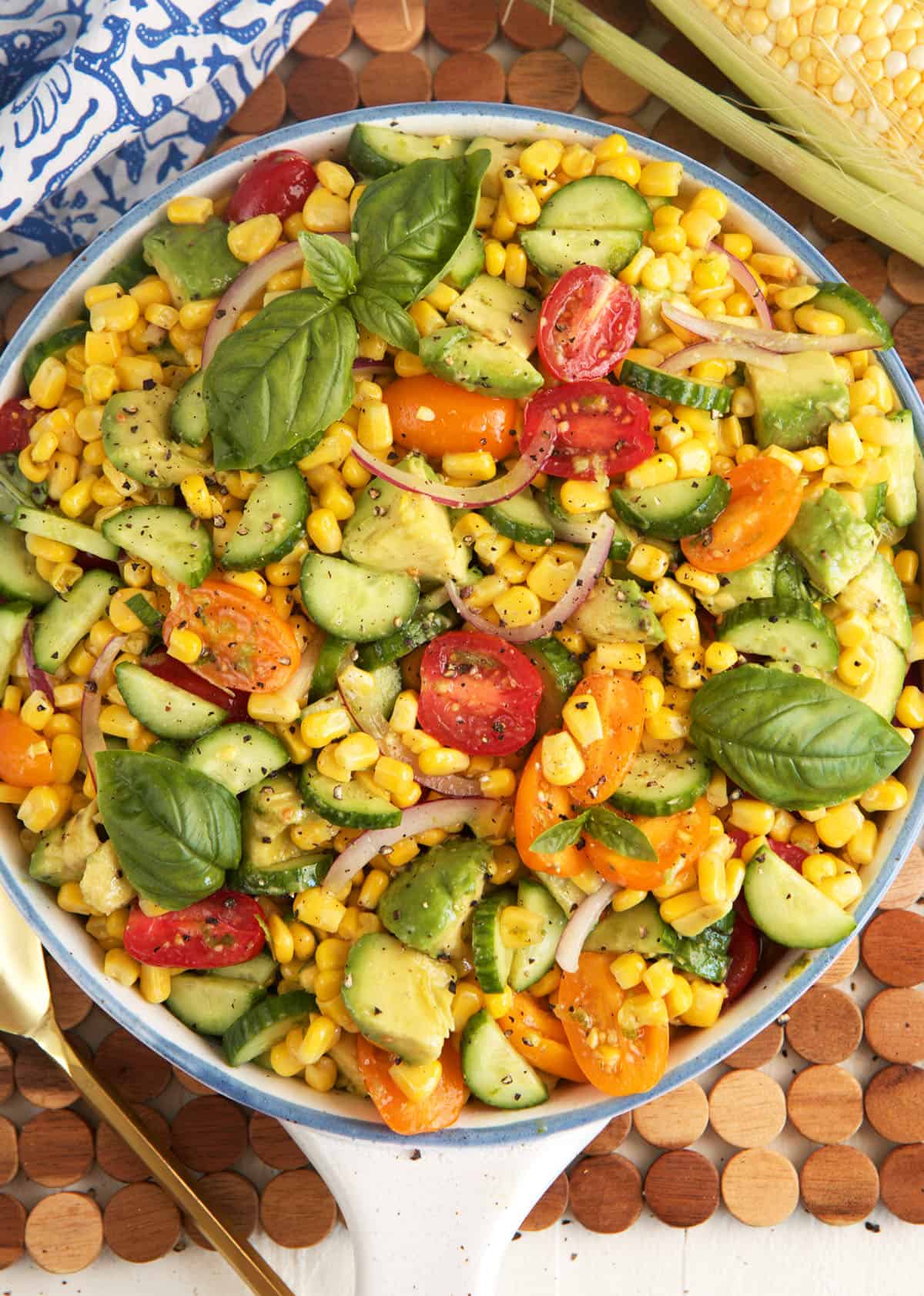 Overhead view of avocado corn salad in bowl with fresh basil leaves for garnish