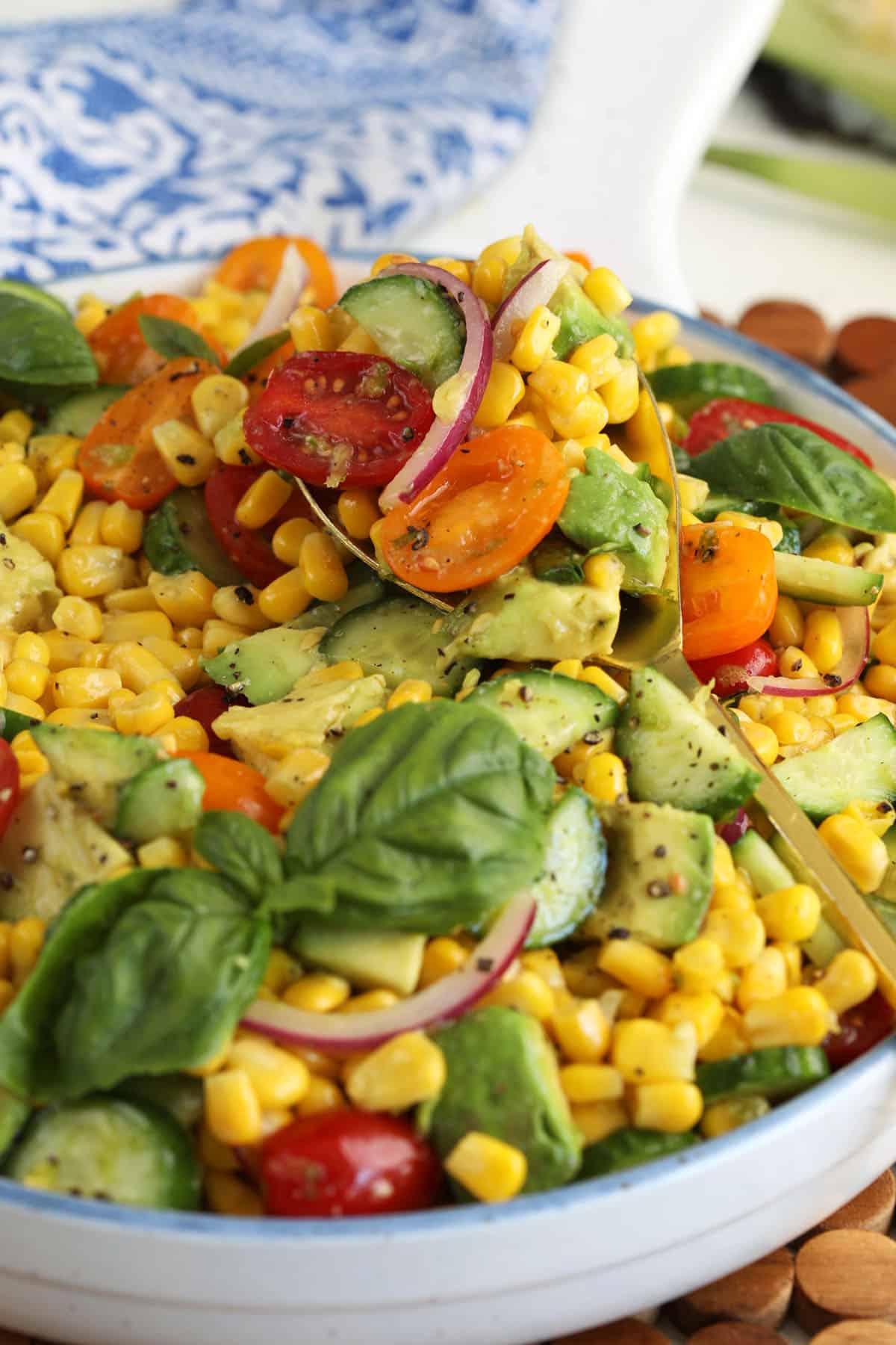 Bowl of avocado corn salad garnished with sprigs of fresh basil