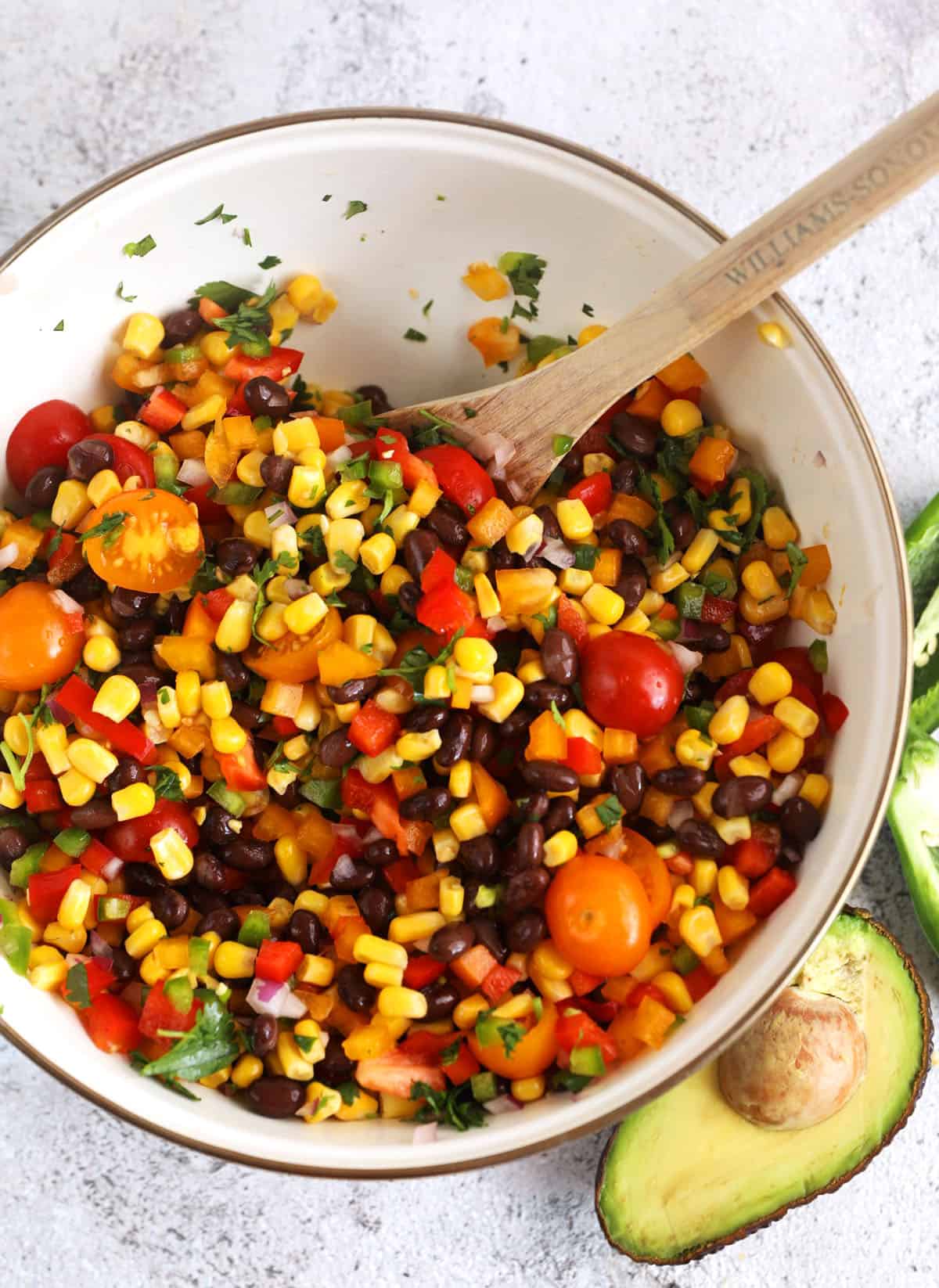 Overhead view of black bean and corn salad in bowl with spoon