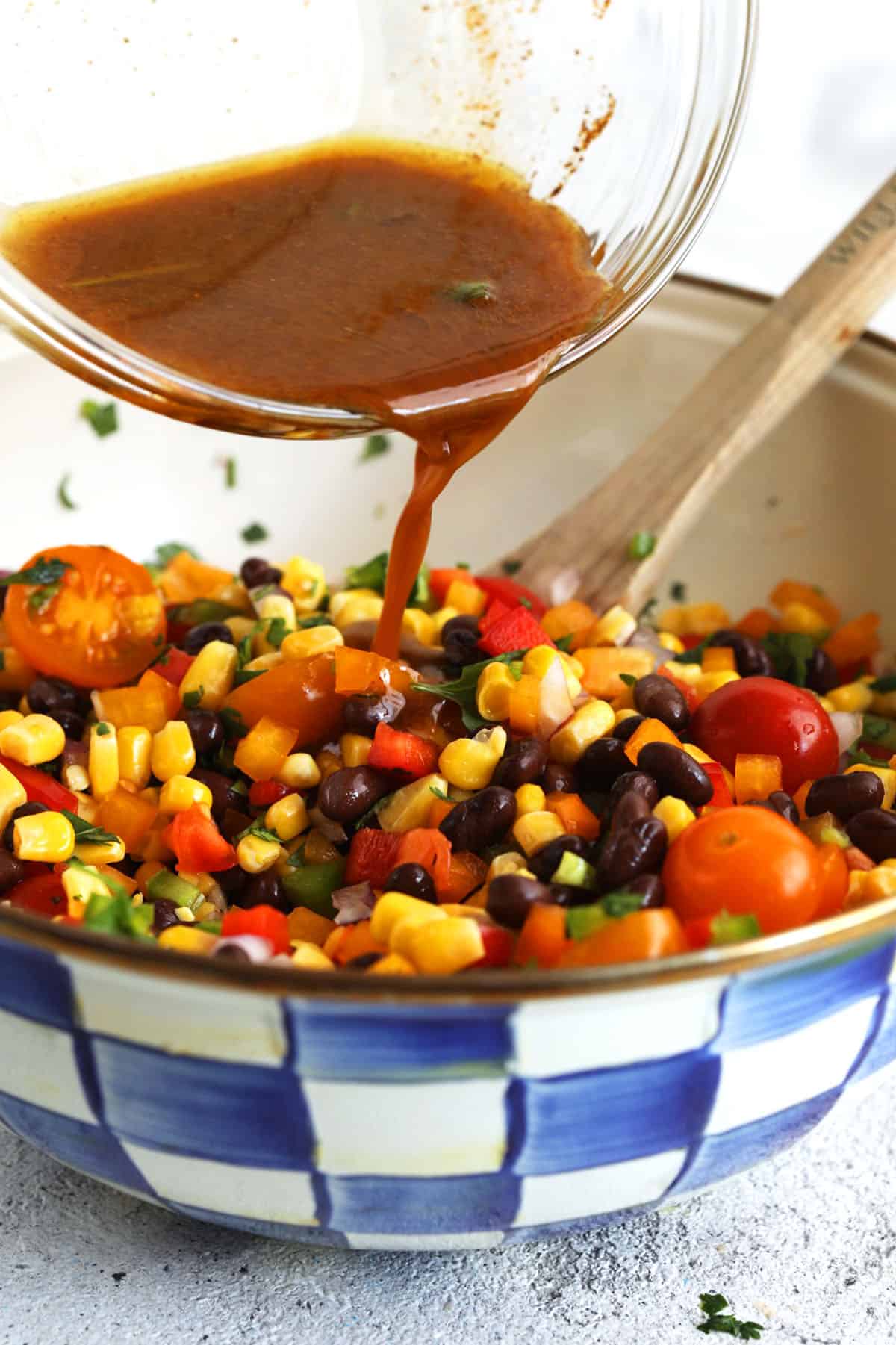 Pouring honey-lime vinaigrette into black bean and corn salad