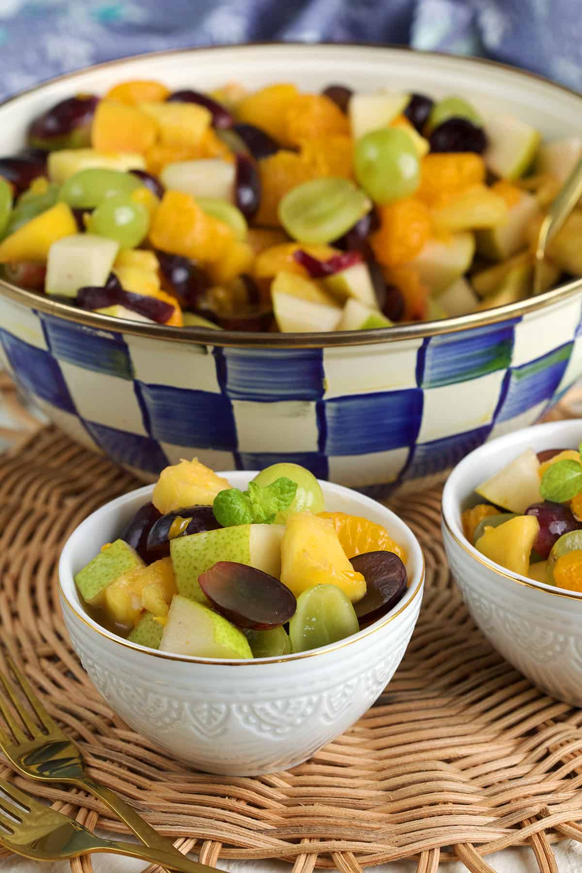 Two small bowls of fruit cocktail in front of serving bowl