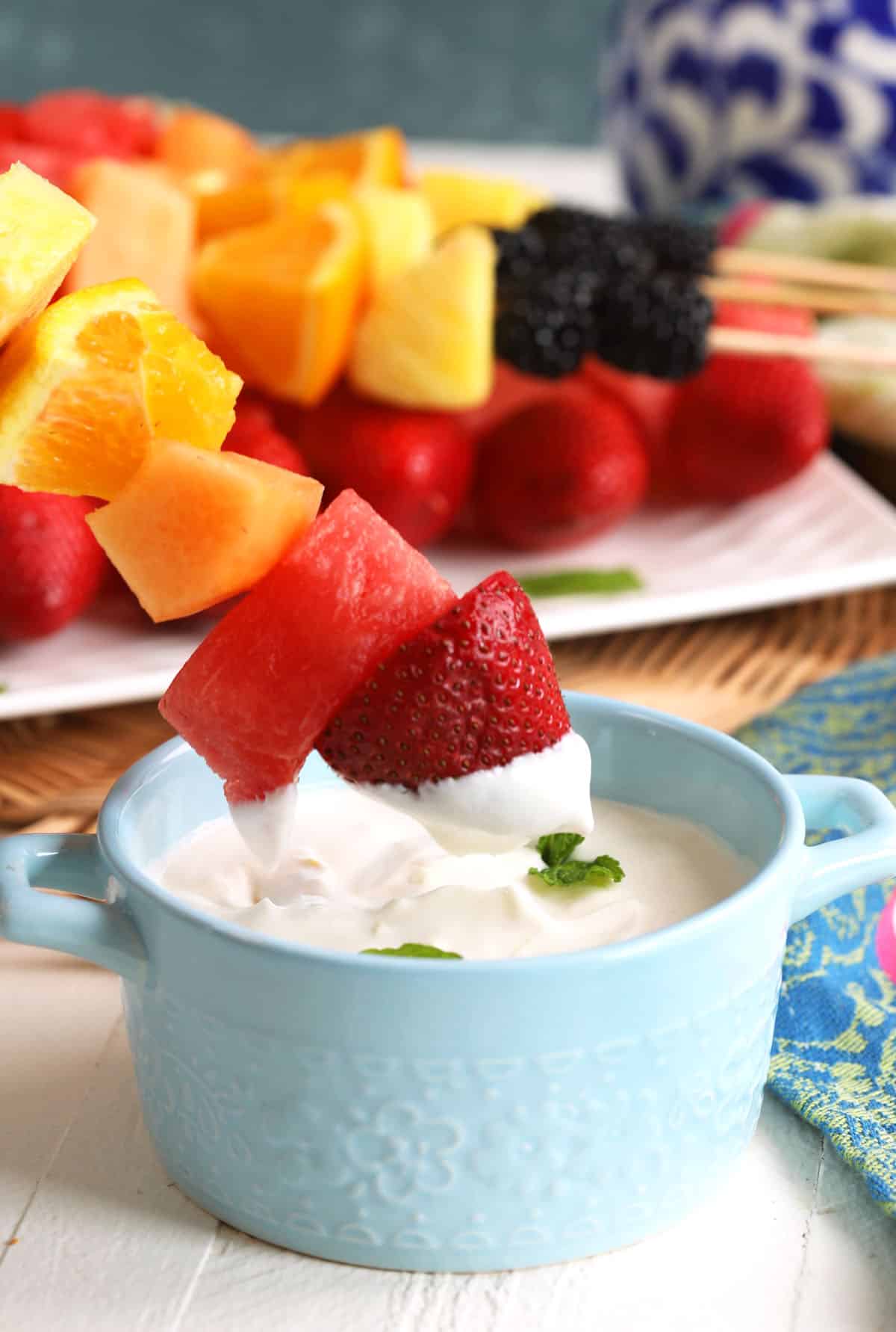 Dipping fruit kabob into Greek yogurt dip