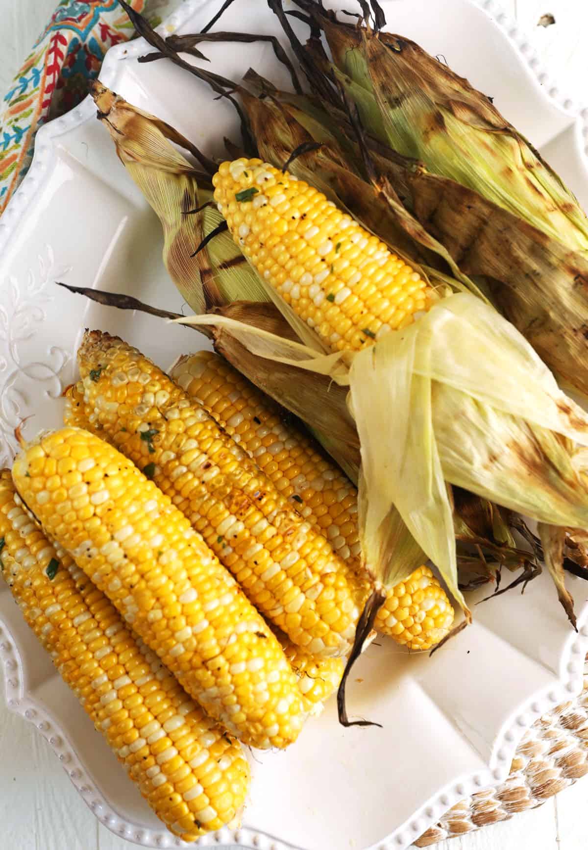 Overhead view of grilled corn, some with husks and some without