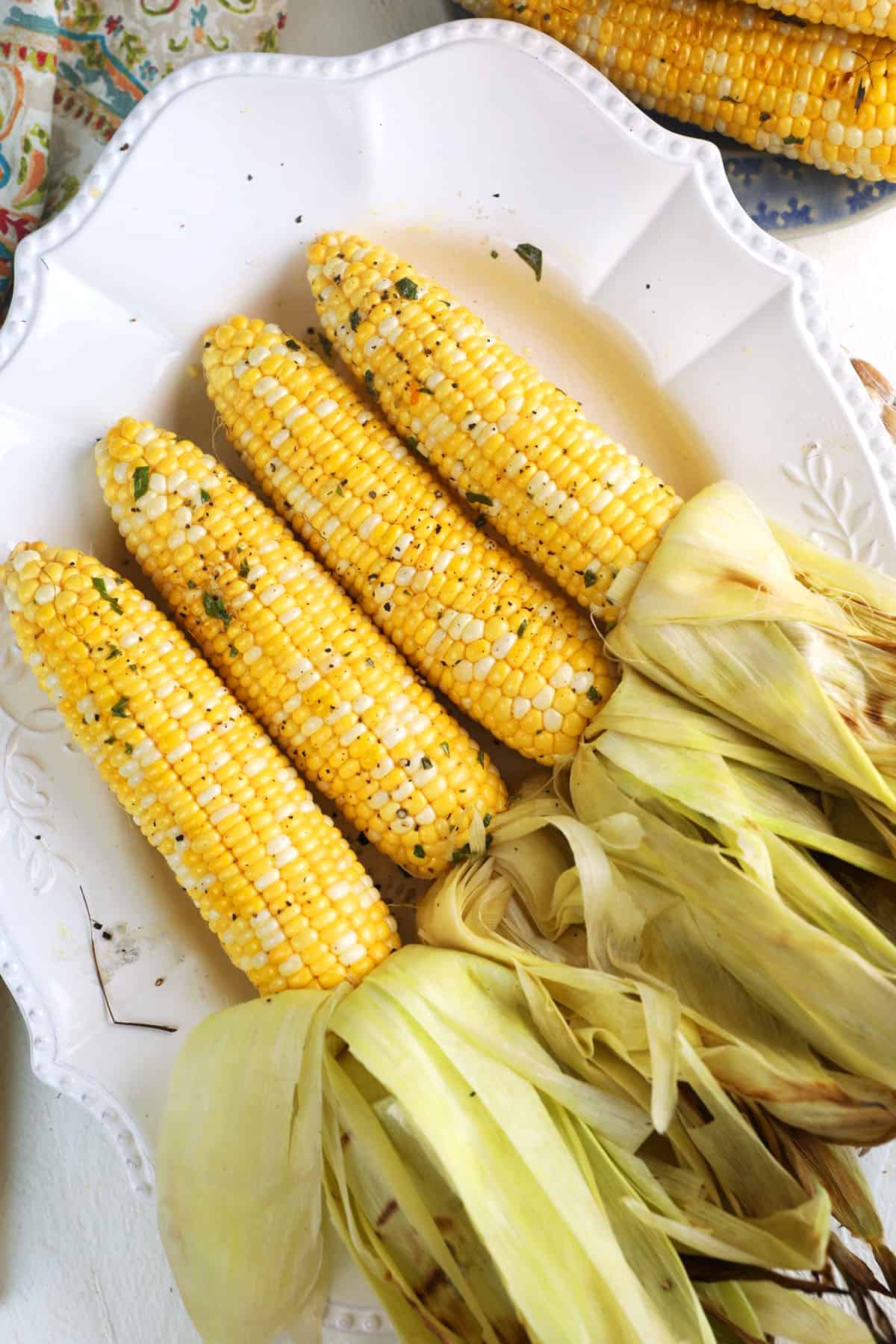 Overhead view of grilled corn on platter with husks peeled back