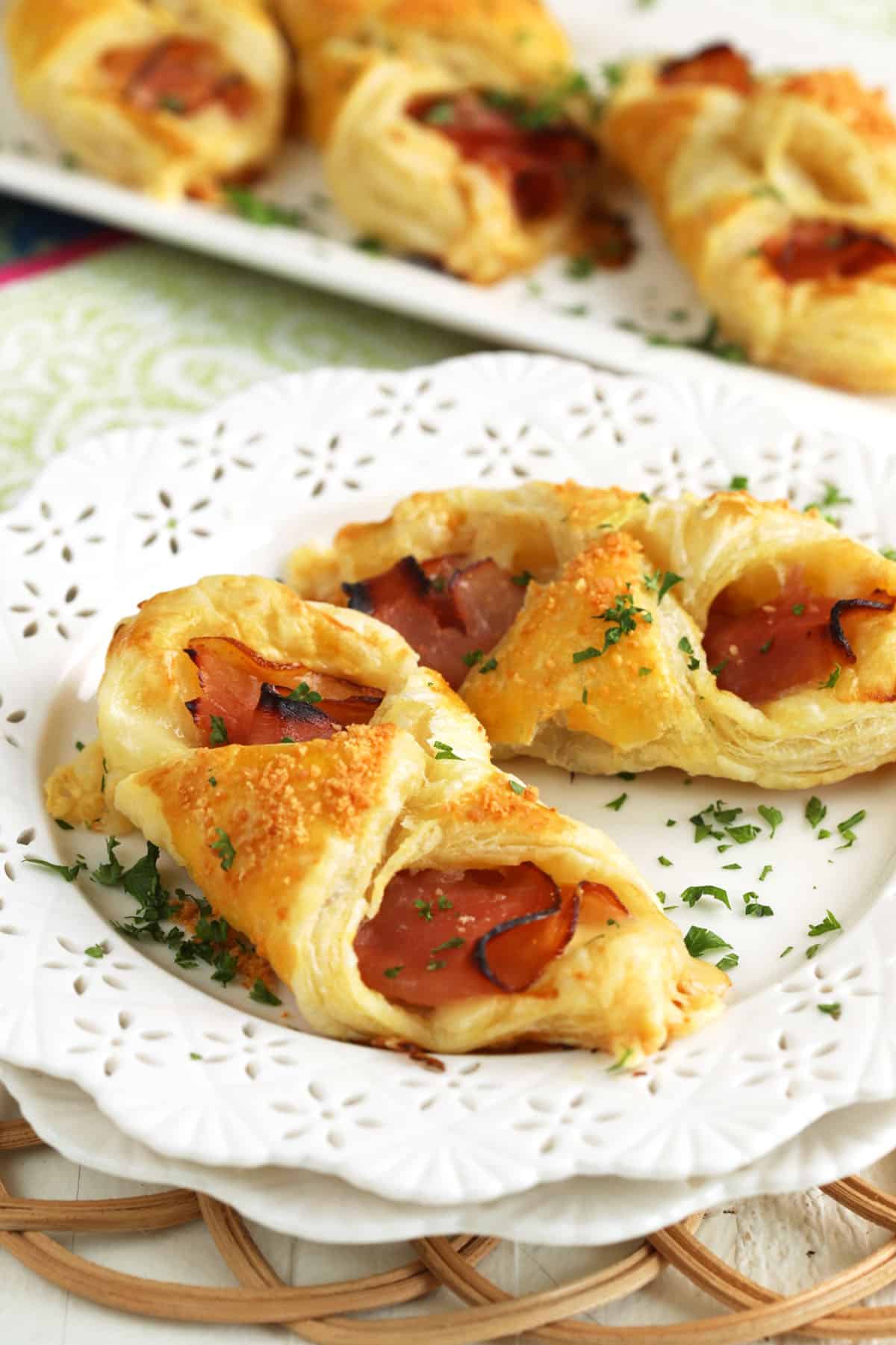 Closeup of 2 ham and cheese croissants on white plate