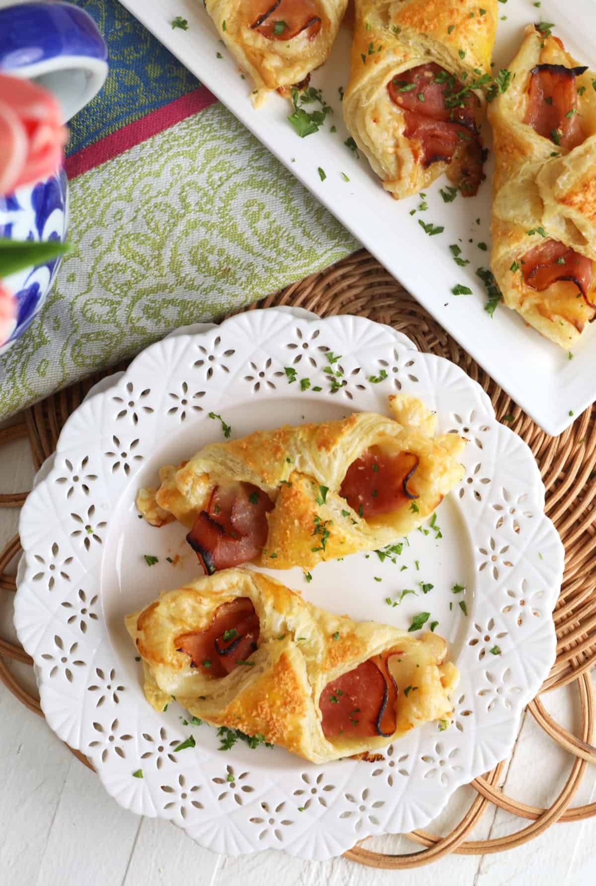 Overhead view of 2 ham and cheese croissants on white plate