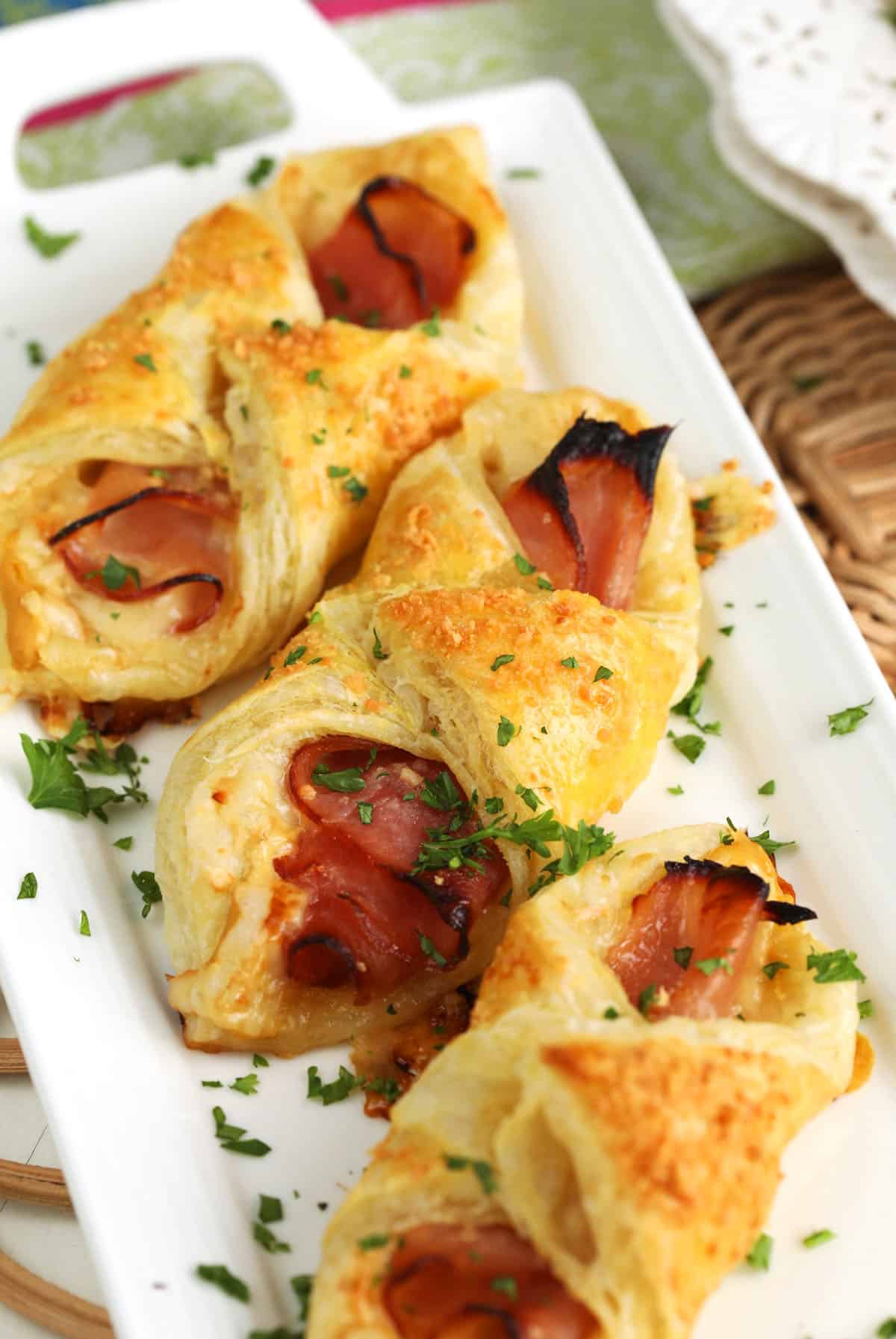 Ham and cheese croissants on white serving platter