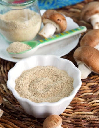 Bowl of mushroom powder, with additional powder in jar in background