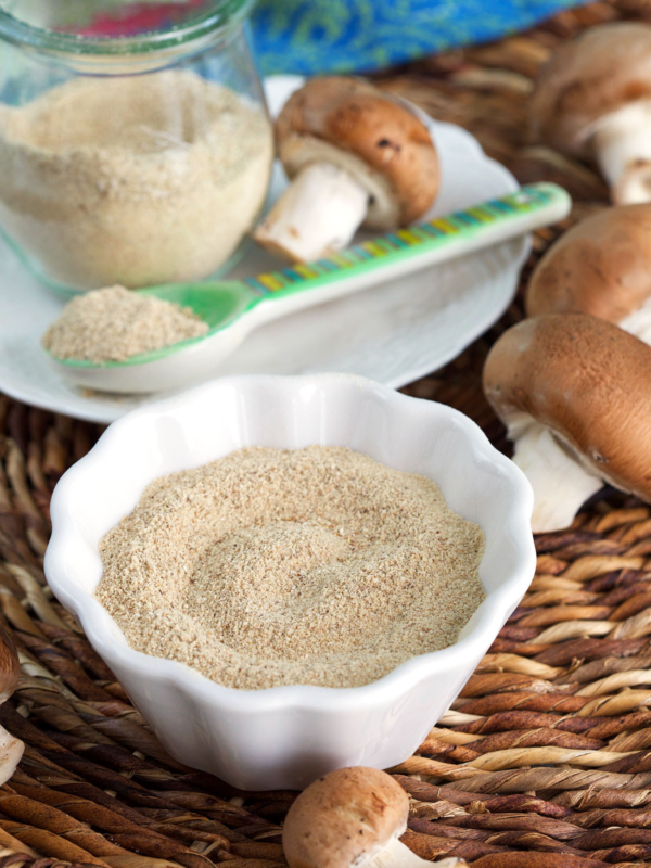 Bowl of mushroom powder, with additional powder in jar in background