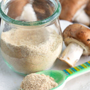 Spoon of mushroom powder set in front of jar