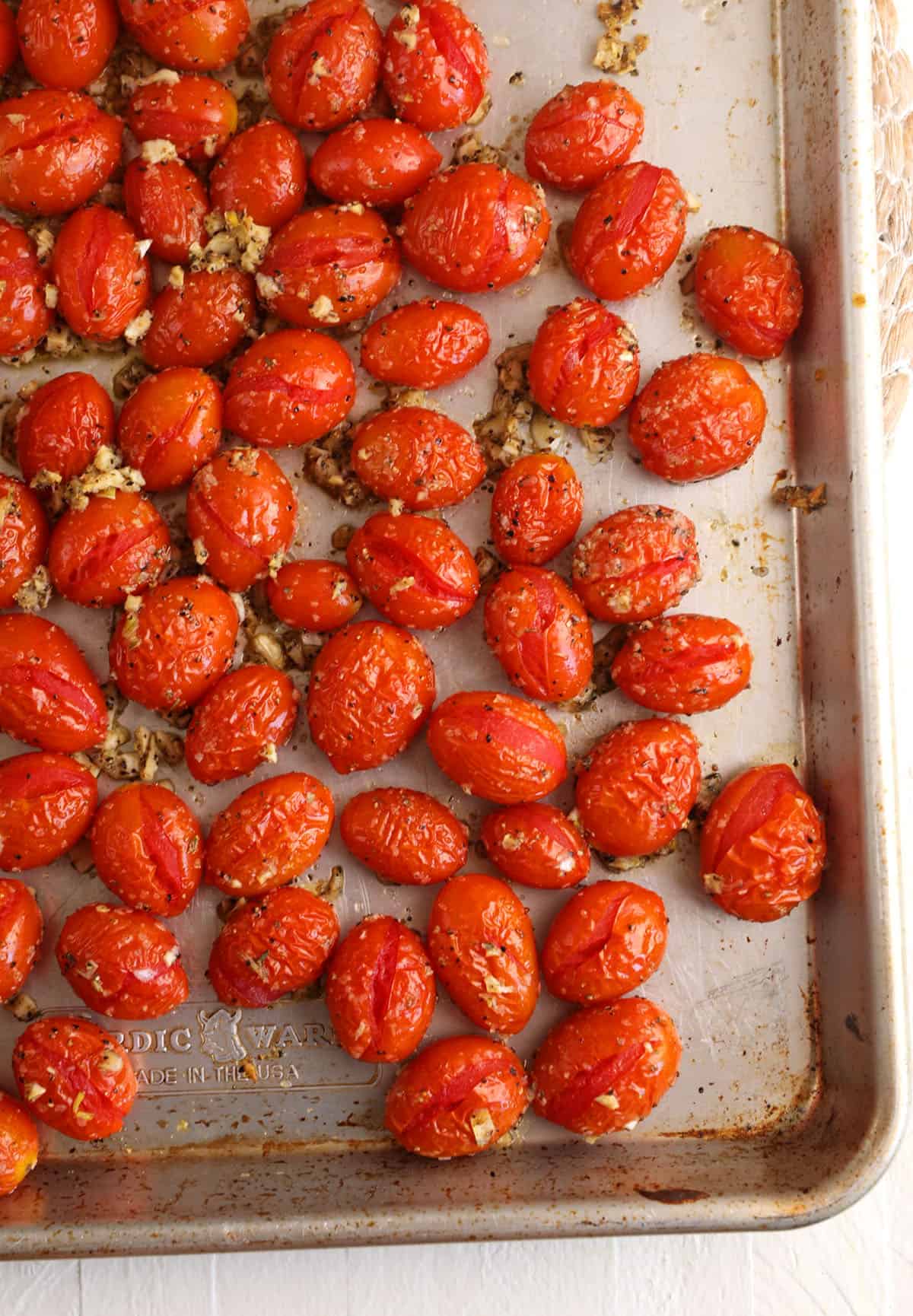 Overhead view of roasted cherry tomatoes on sheet pan