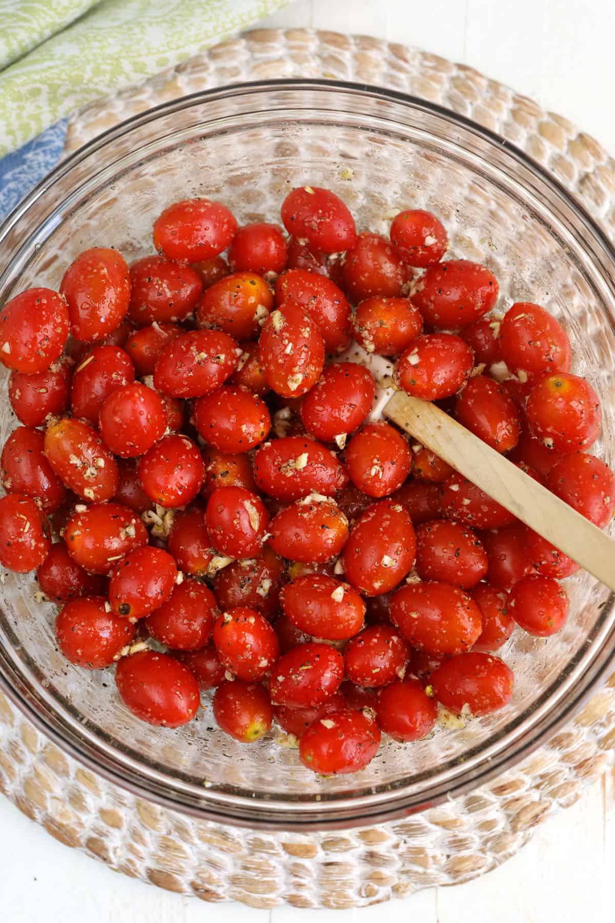 Overhead view of cherry tomatoes in bowl with oil and seasonings