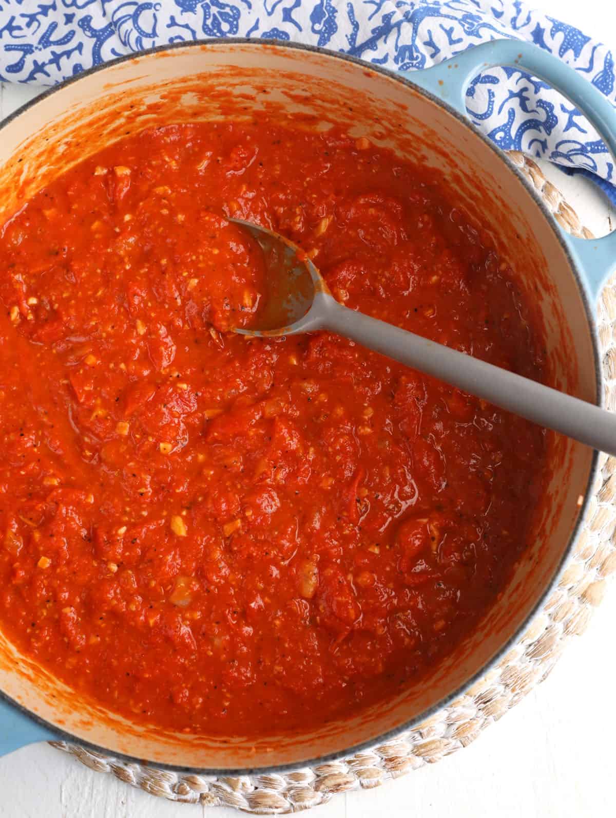 Overhead view of roasted tomato sauce in pot with spoon