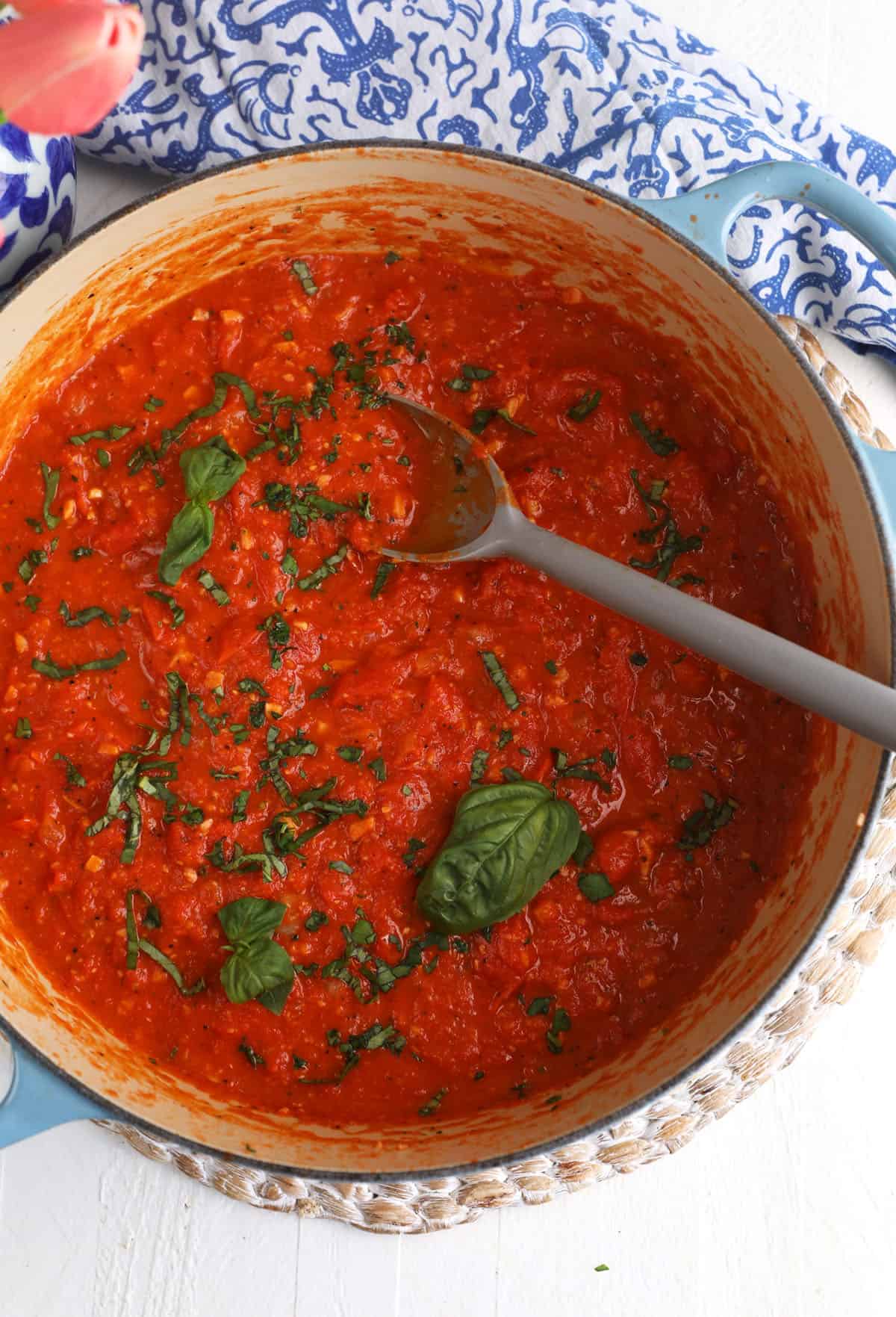 Overhead view of roasted tomato sauce in pot with fresh herbs