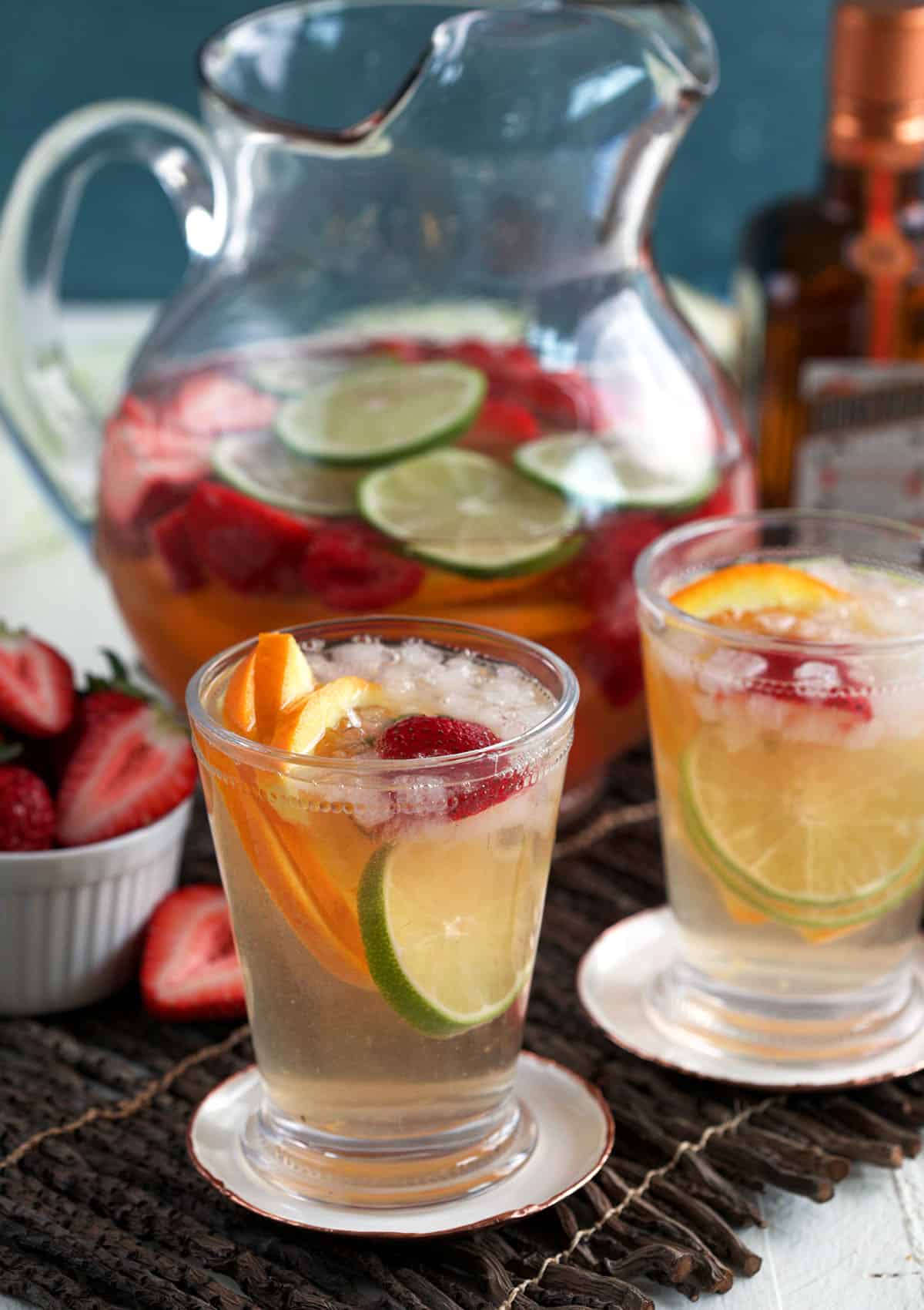 Two glasses of rosé sangria with pitcher in background