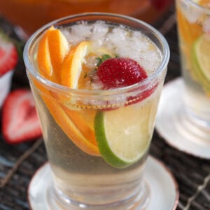 Rosé sangria in glass with ice, lime and orange slices, and strawberry