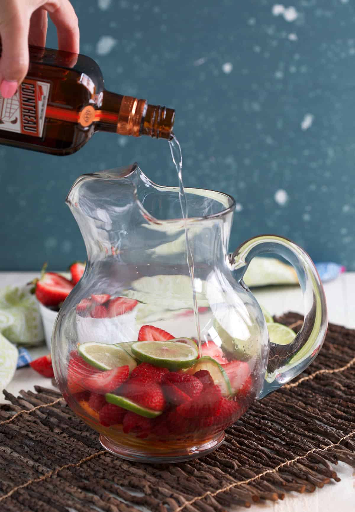 Pouring Cointreau into pitcher for rosé sangria