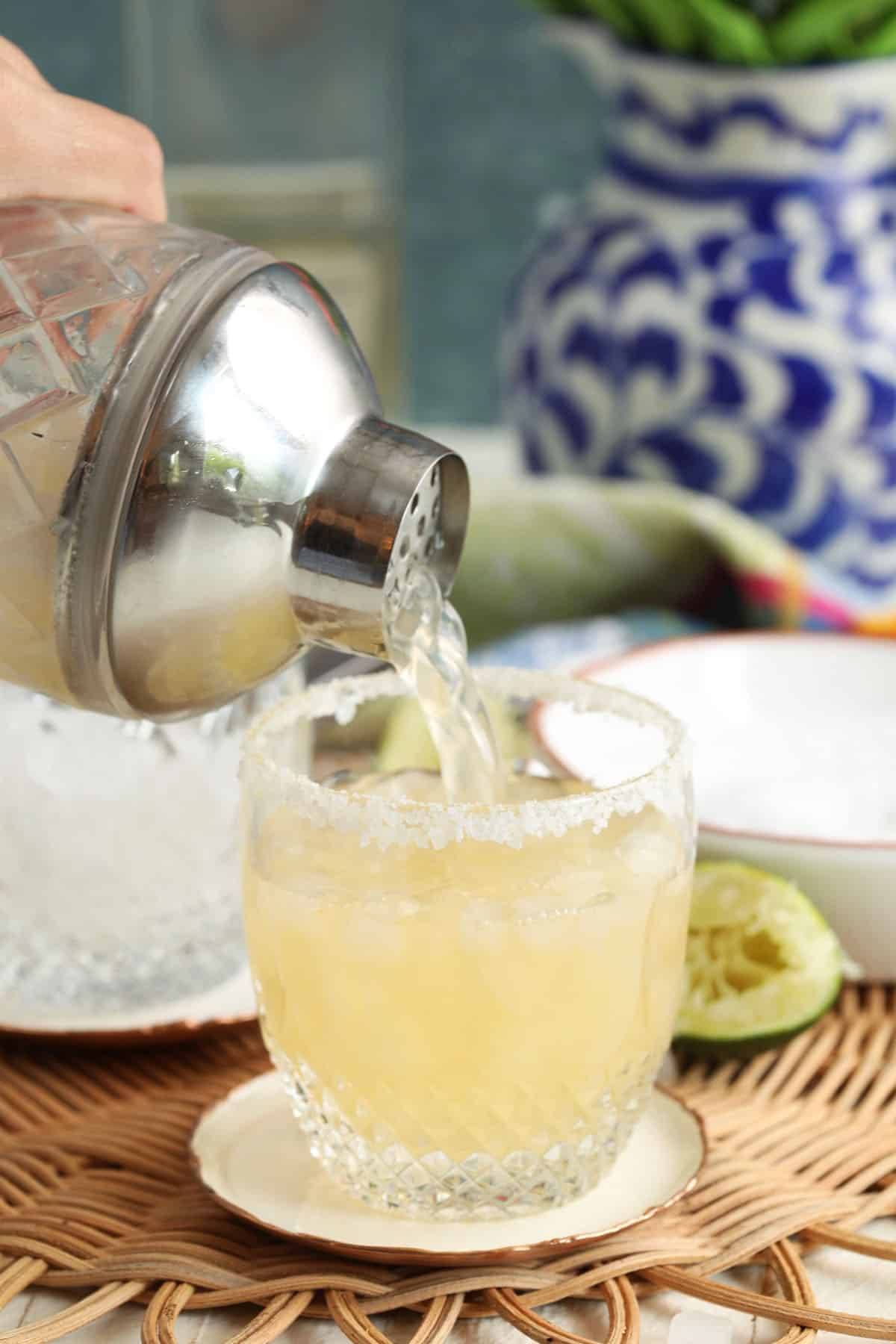 Pouring margarita from shaker into glass with salted rim