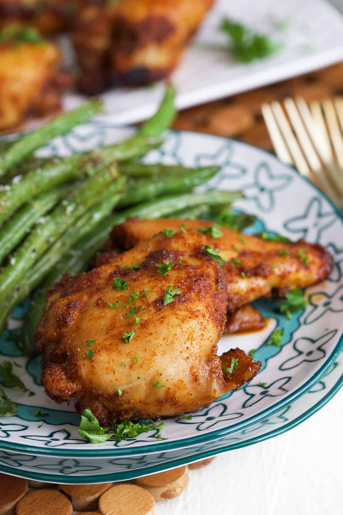 Sweet and spicy boneless chicken thighs on plate with green beans