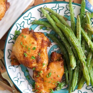 Overhead view of sweet and spicy boneless chicken thighs on plate with green beans