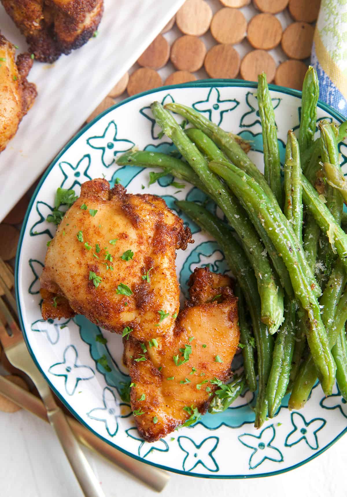 Overhead view of sweet and spicy boneless chicken thighs on plate with green beans