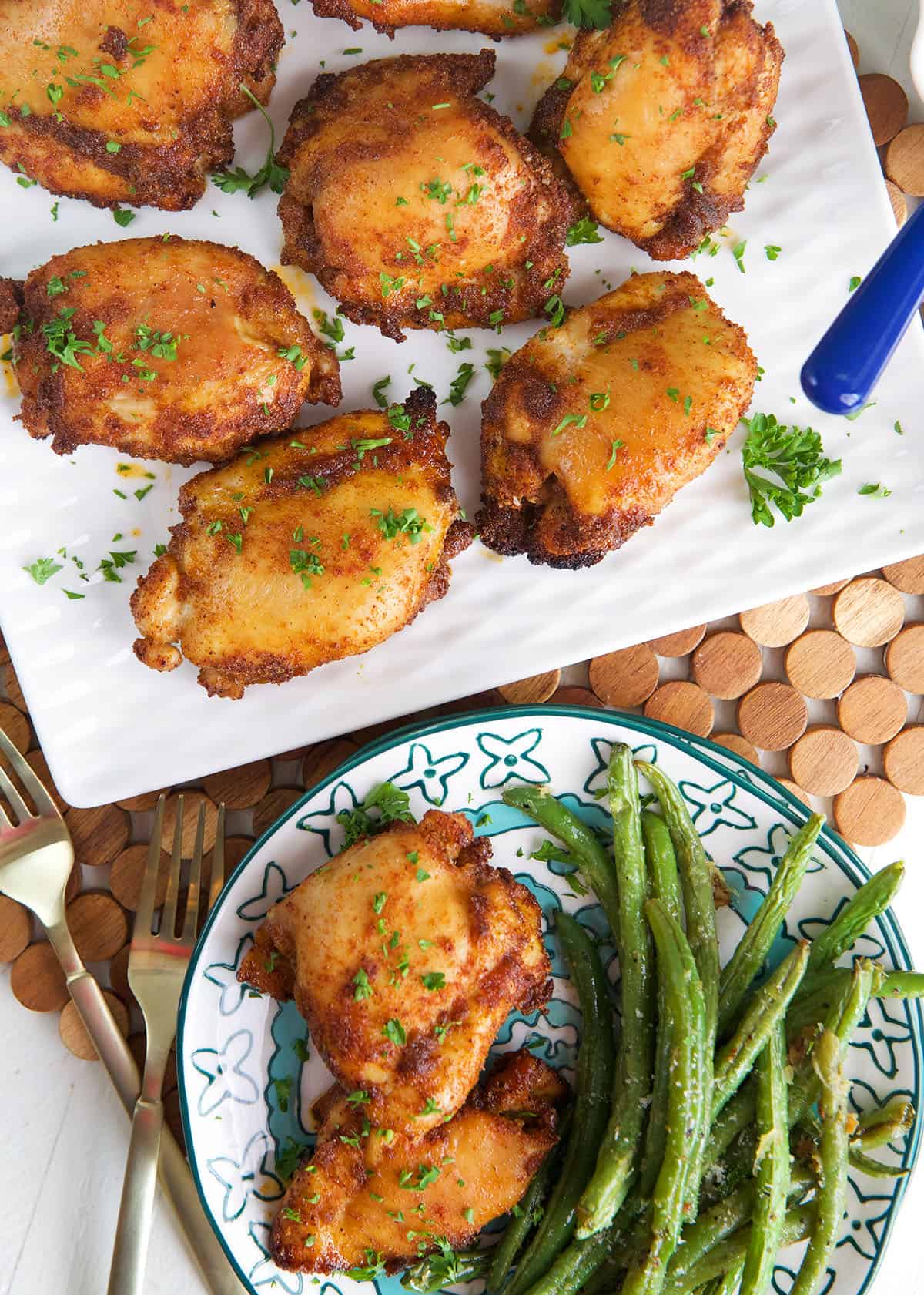 Overhead view of sweet and spicy boneless chicken thighs on platter and plate