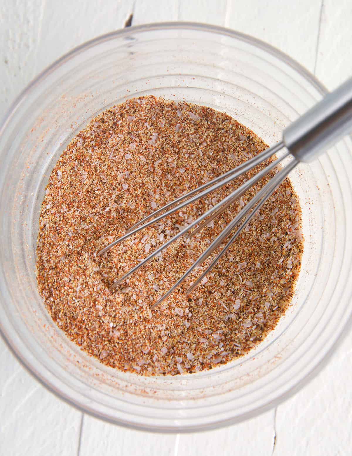 Overhead view of seasoning mixture for sweet and spicy boneless chicken thighs in mixing bowl with whisk