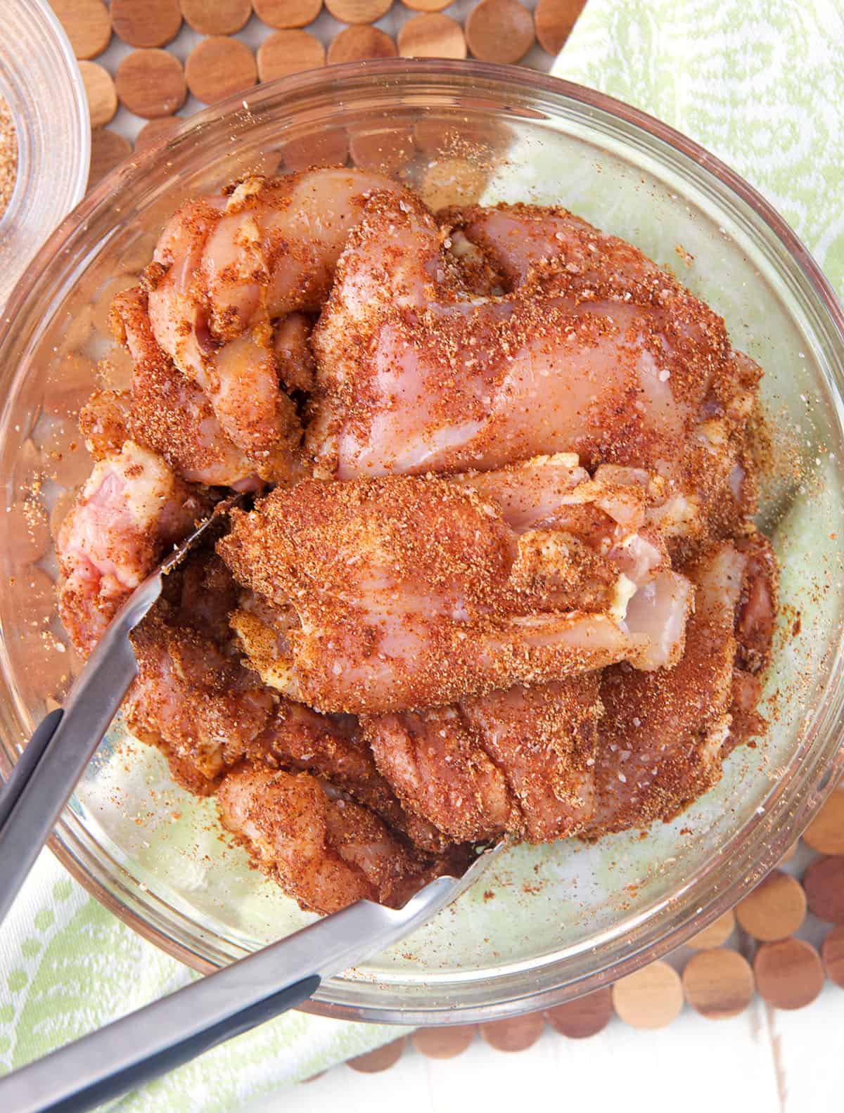 Seasoning chicken thighs in mixing bowl