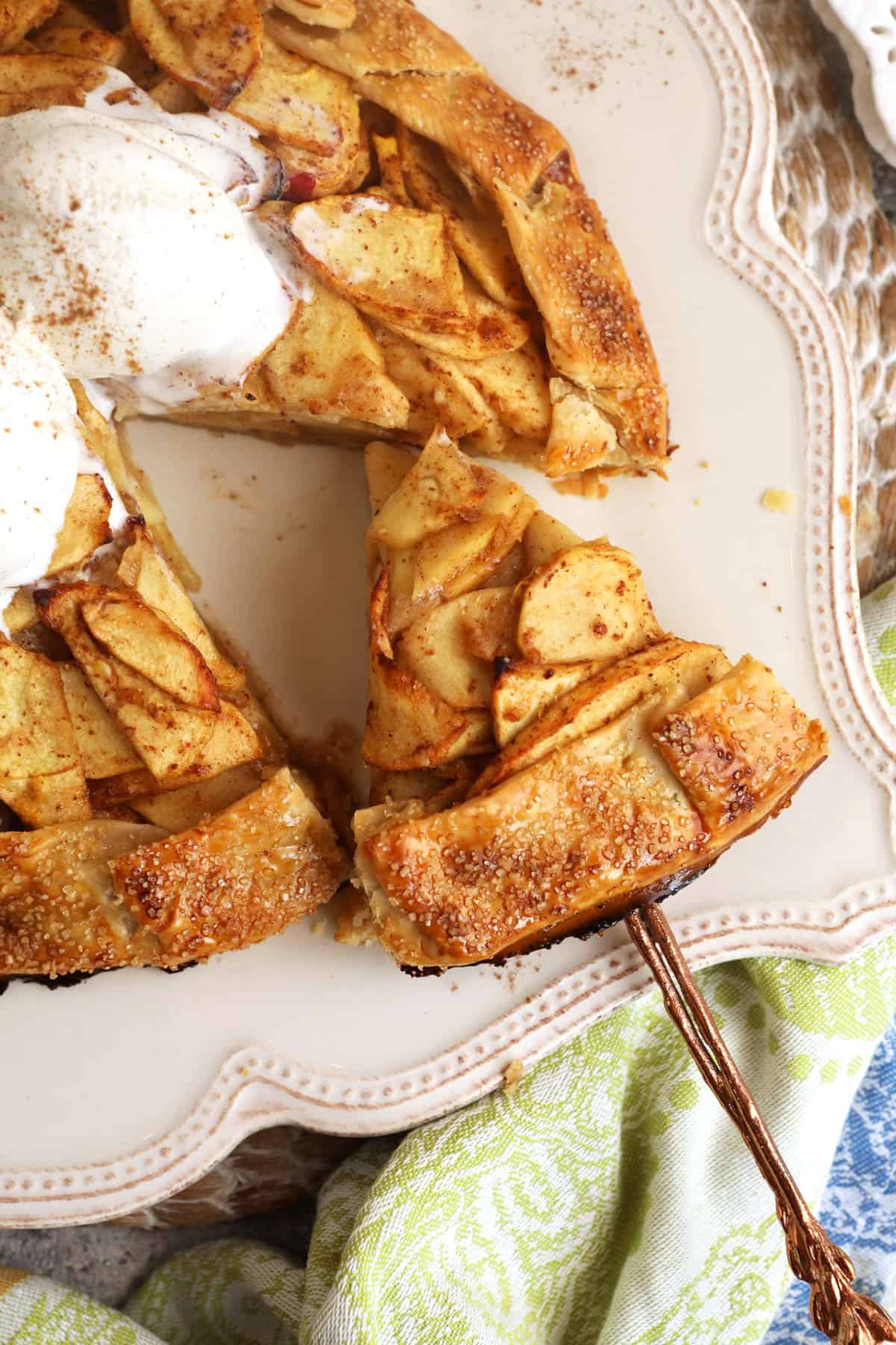 Spatula lifting slice of apple galette from platter