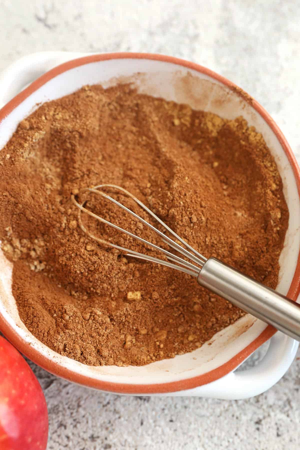 Overhead view of apple pie spice in bowl with whisk