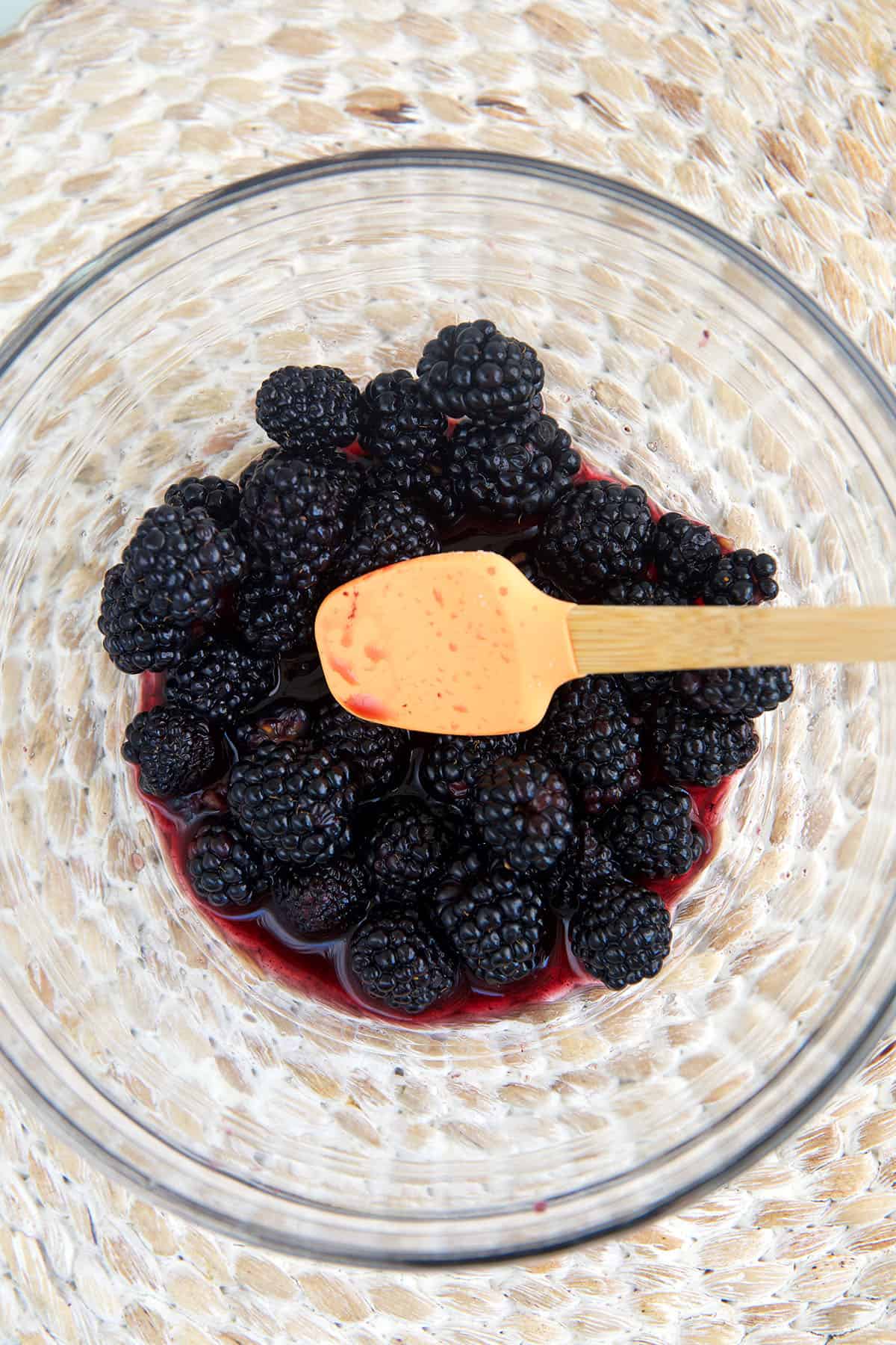 Overhead view of blackberries macerating in bowl with wine and sugar