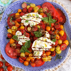 Overhead view of burrata caprese on blue serving platter