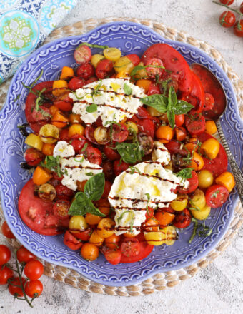 Overhead view of burrata caprese on blue serving platter