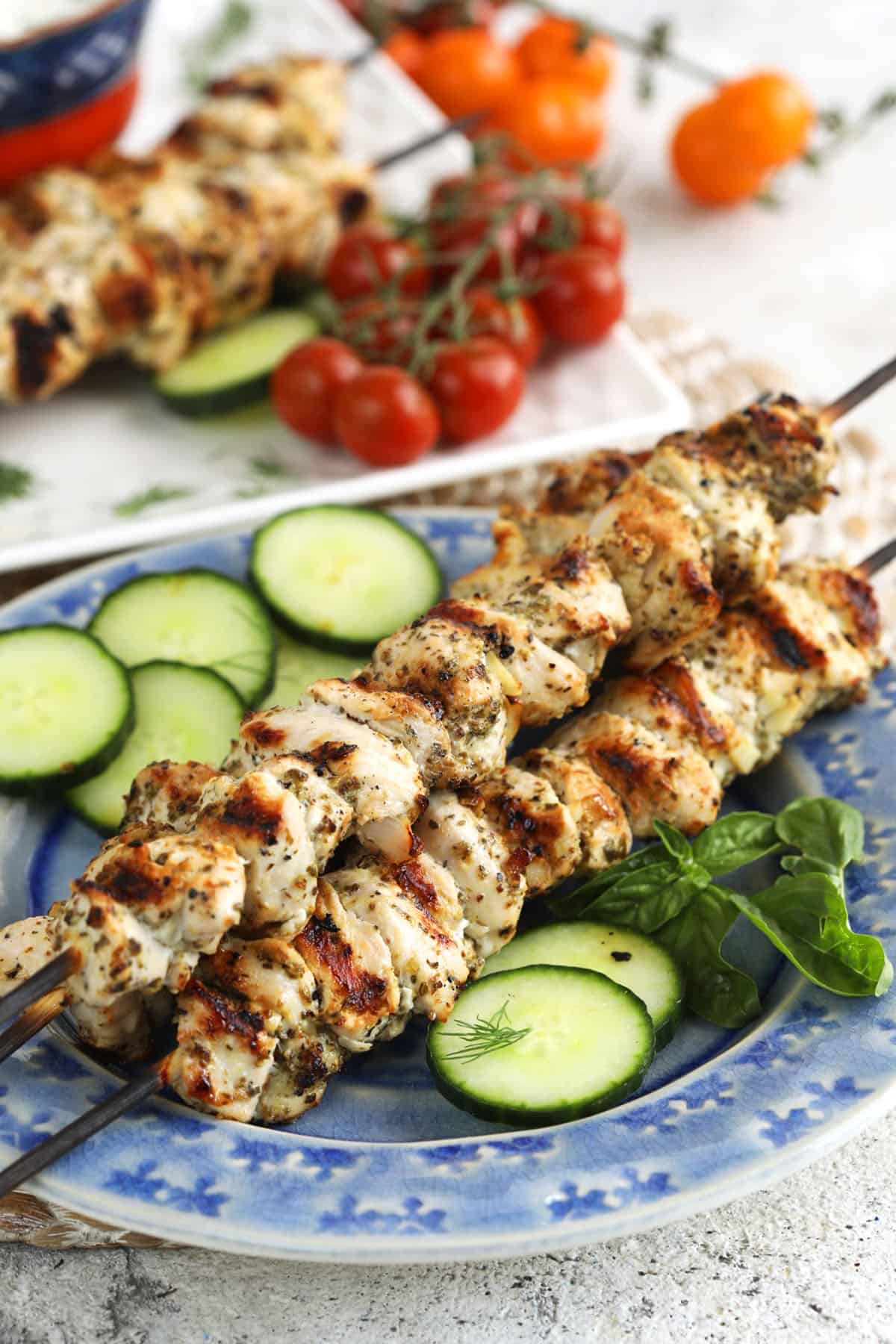 Grilled chicken souvlaki on platter with cucumbers