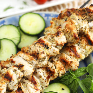 Chicken souvlaki skewers on platter with cucumbers